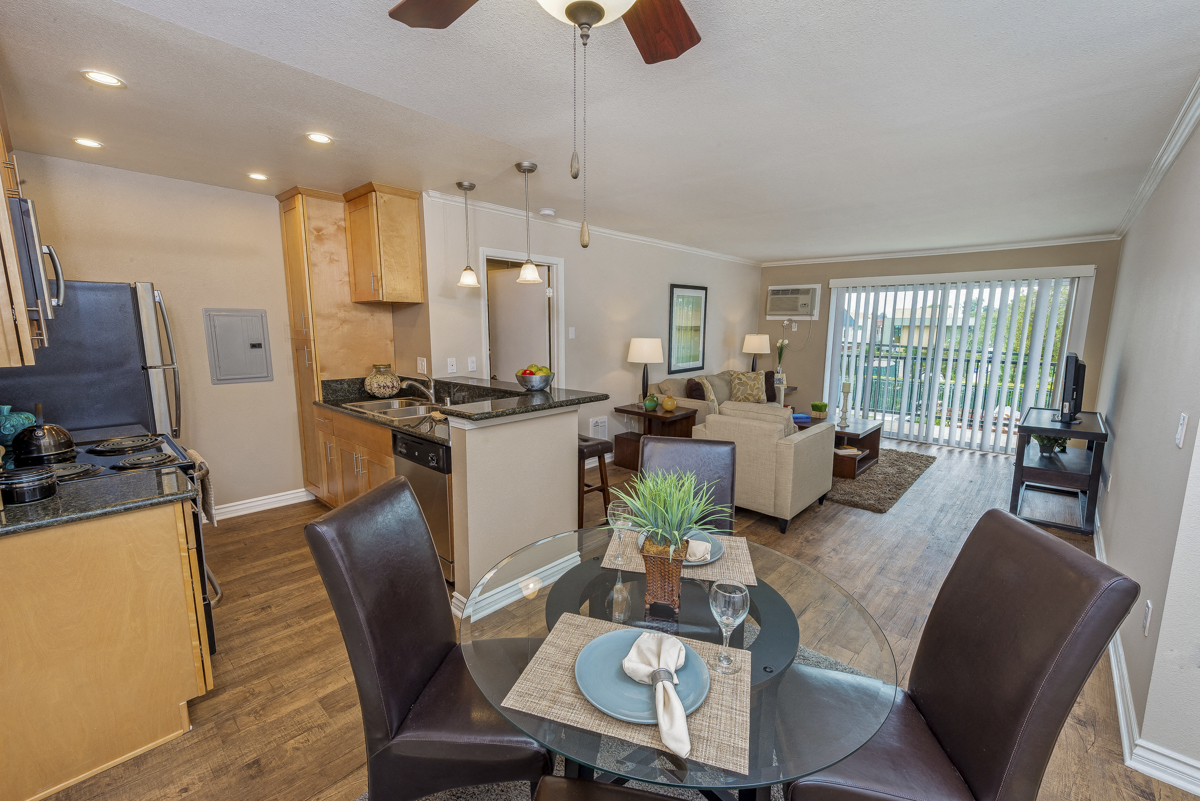 the view of a living room with a dining table and a kitchen