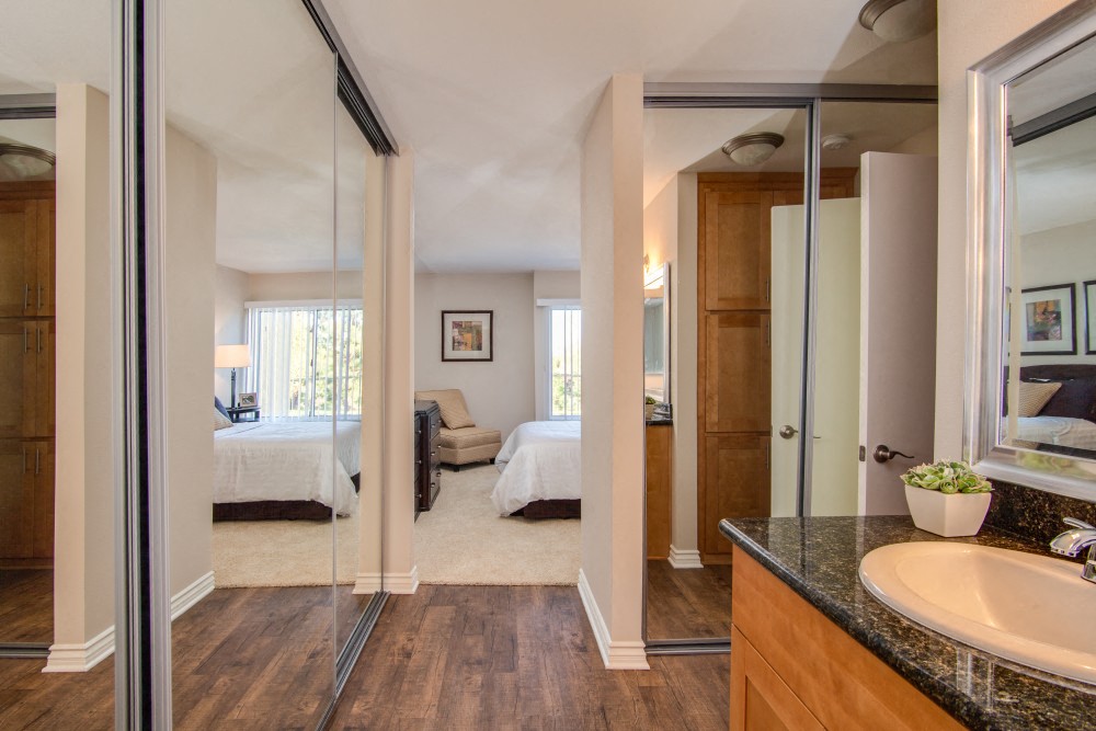 a bathroom with a sink and a mirror in a room with a bedroom