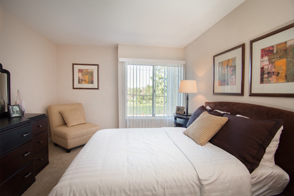 a bedroom with a bed and a chair and a window