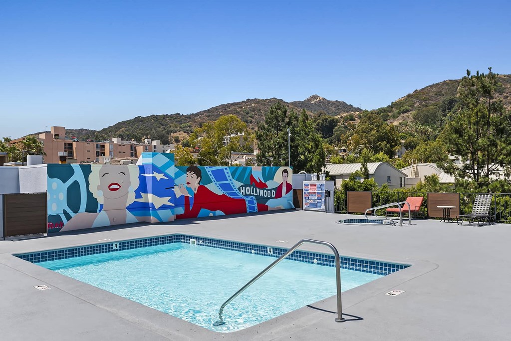 a swimming pool is next to a mural on a wall