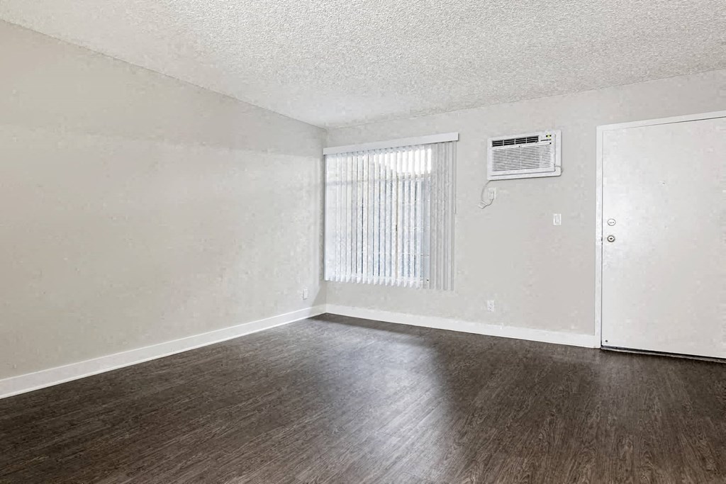 an empty living room with wood floors and a window