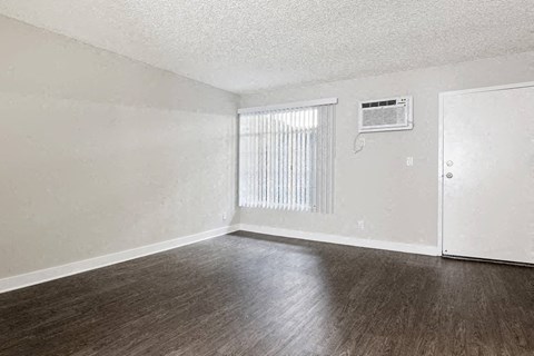 an empty living room with wood floors and a window