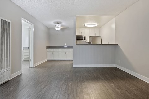 an empty living room and kitchen with wood flooring