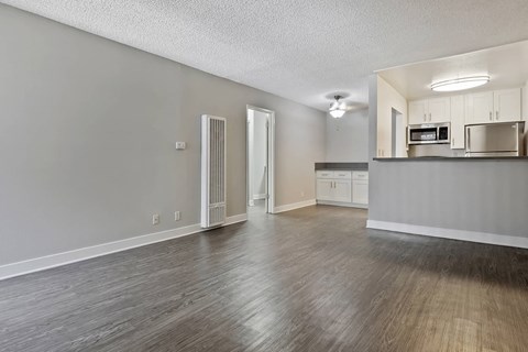an empty living room and kitchen with wood floors