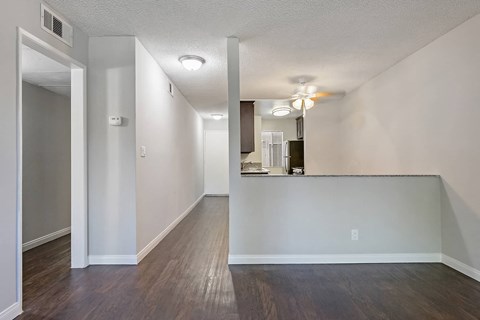 an empty living room and kitchen with hard wood floors and white walls