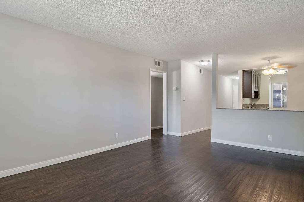 an empty living room with hard wood floors and a kitchen
