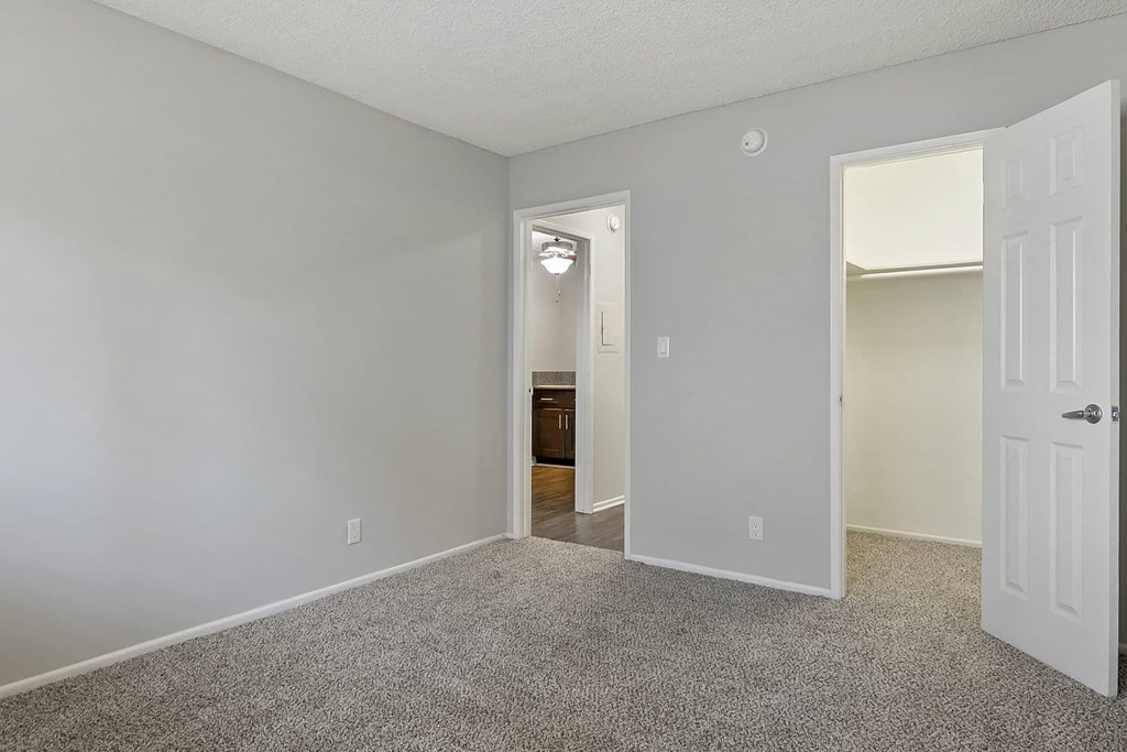 an empty bedroom with a door to a bathroom