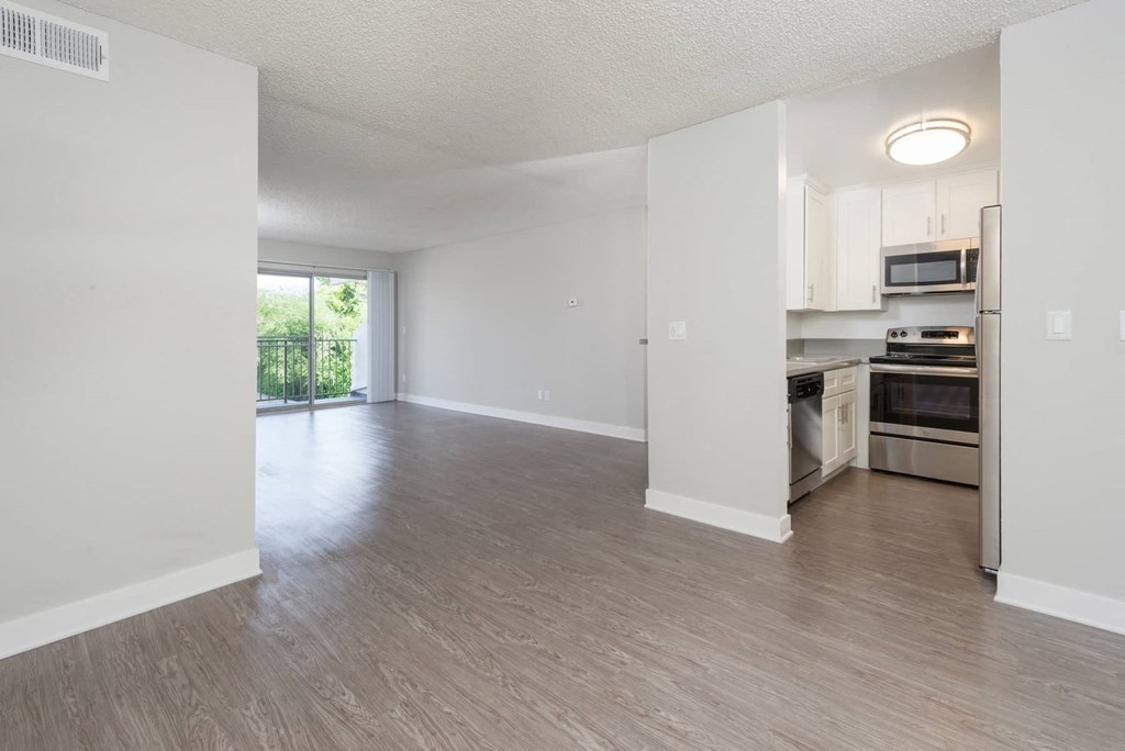 an empty living room and kitchen with wood flooring