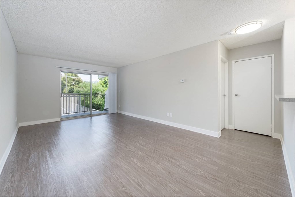 an empty living room with a door to a balcony
