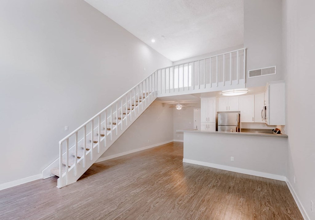 a living room with a staircase and a kitchen with a counter top