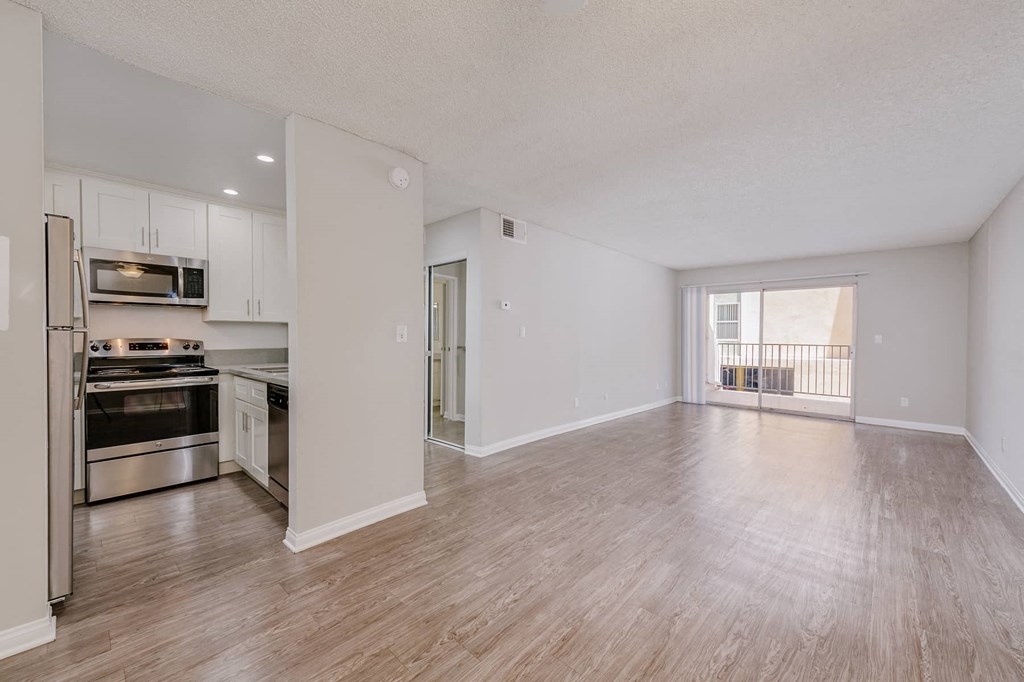 an empty living room and kitchen with wood floors