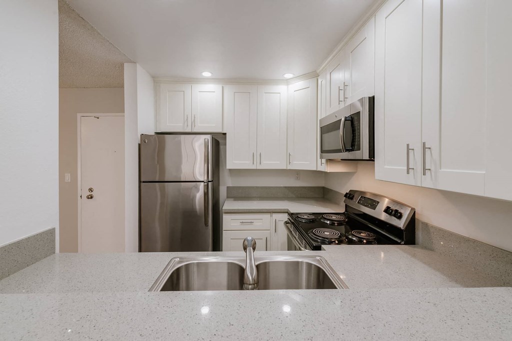 a kitchen with white cabinets and stainless steel appliances