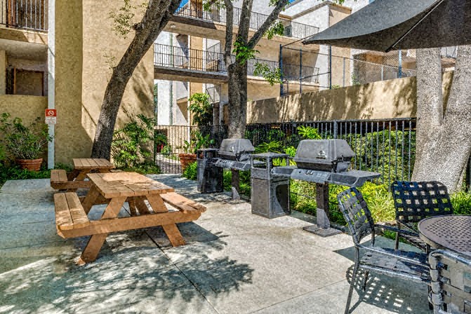 a patio with a picnic table and barbecue grill