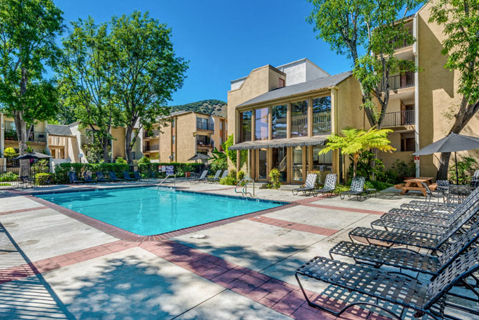 a pool with lounge chairs and a building in the background