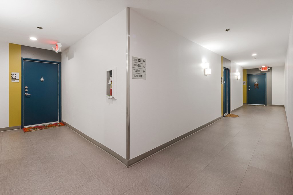 a hallway with two blue doors and a white wall and a tiled floor