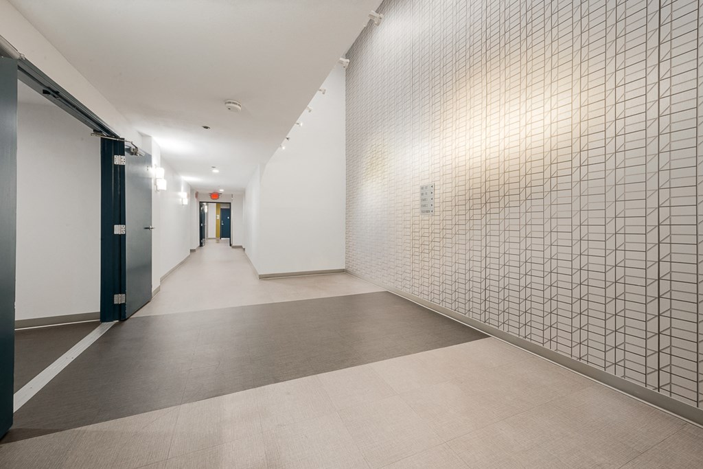 a long hallway with white walls and gray flooring and doors