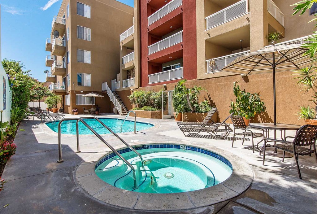 a jacuzzi pool and patio with an apartment building in the background