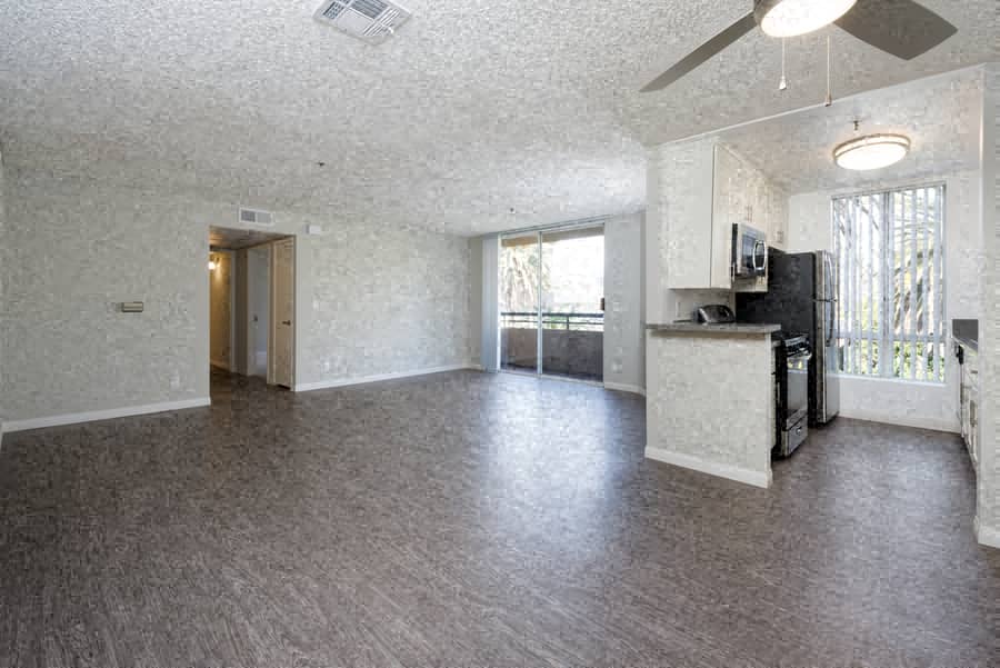 A spacious living room with a kitchen area in the background.
