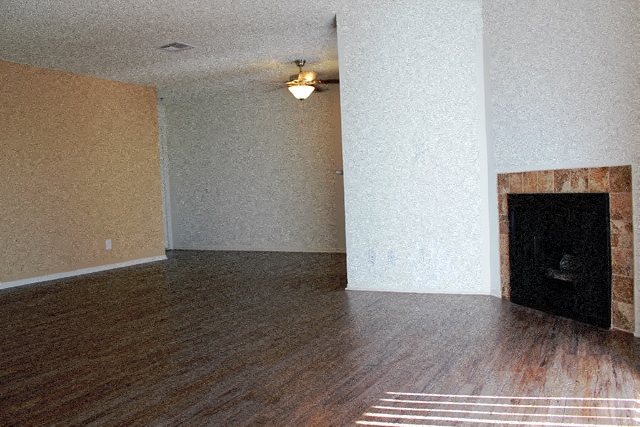 A room with a fireplace and wood flooring.