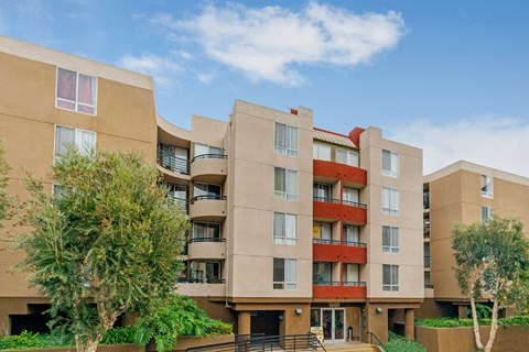 A modern apartment building with a red accent on the balconies.