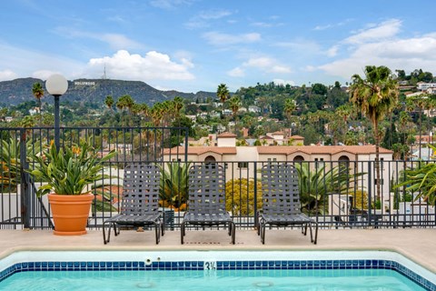 A pool with chairs and a view of a mountain in the background.