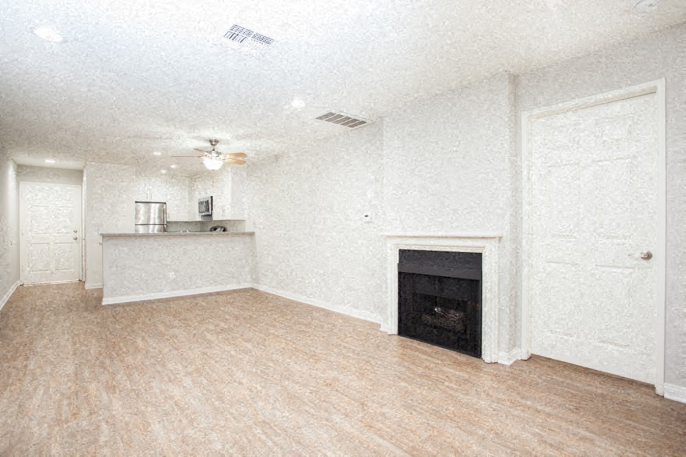an empty living room with a fireplace and a kitchen