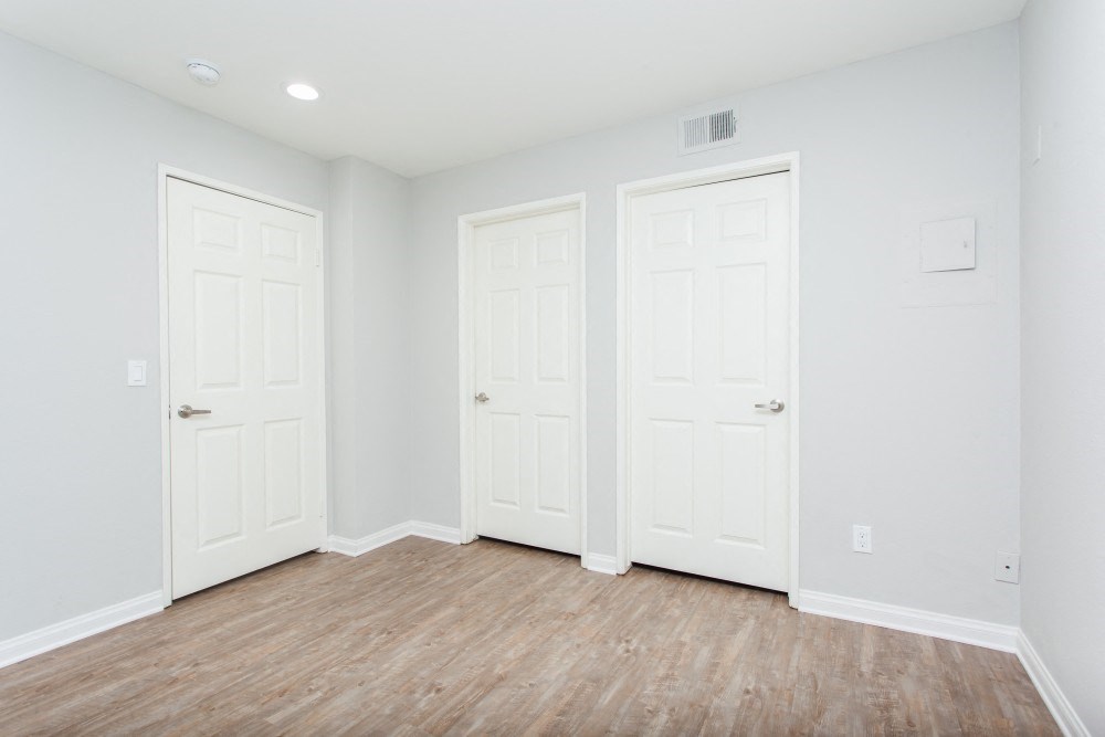 an empty room with three white doors and a wooden floor