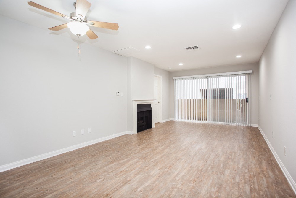an empty living room with a ceiling fan and a window