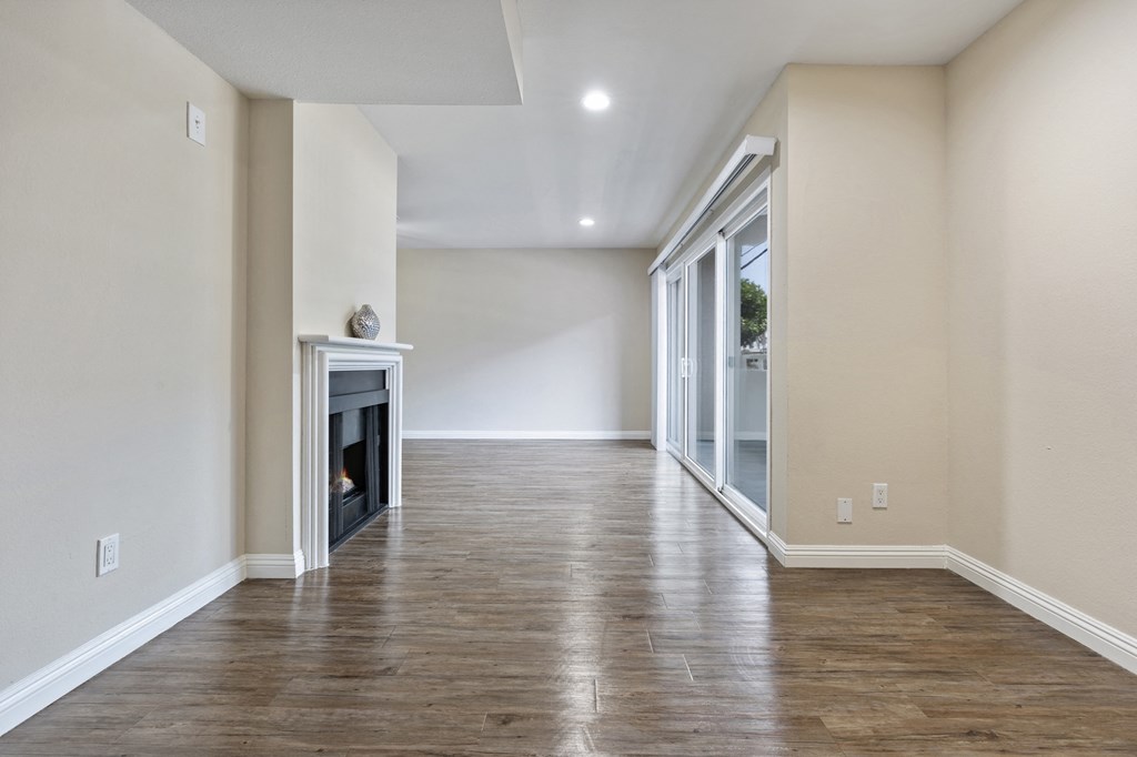 an empty living room with a fireplace and sliding glass doors