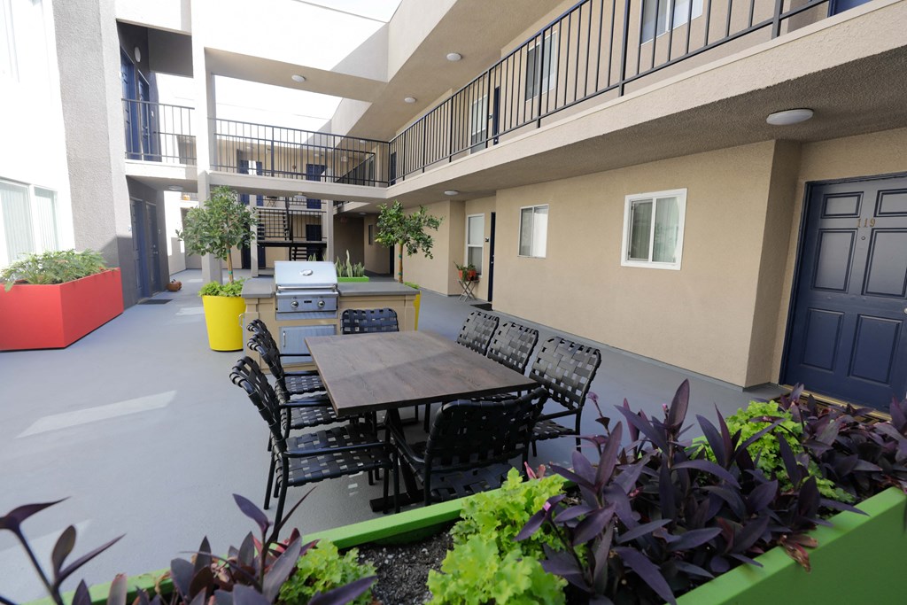 an outdoor patio with a table and chairs and a grill