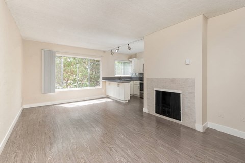 an empty living room with a fireplace and a kitchen