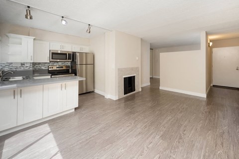an empty living room with a kitchen and a fireplace