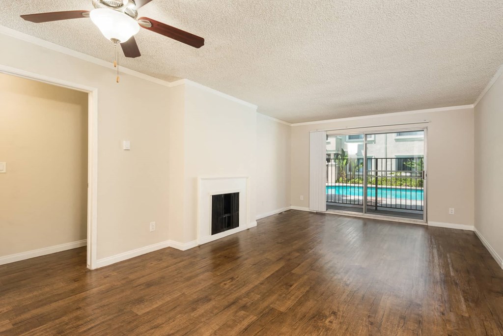 an empty living room with a fireplace and a sliding door to a pool