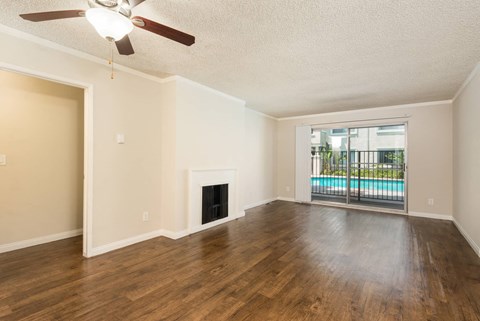 an empty living room with a fireplace and a sliding door to a pool