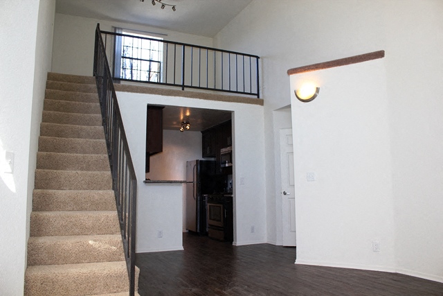 the entryway of a house with a staircase and a door leading to a kitchen