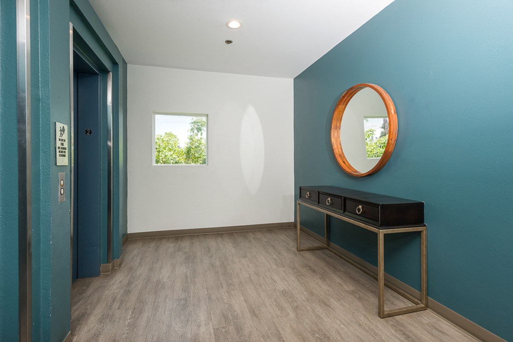 a hallway with a blue wall and a mirror and a blue door