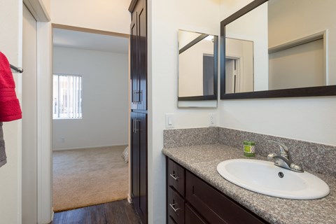 a bathroom with a sink and a mirror and a hallway to a bedroom
