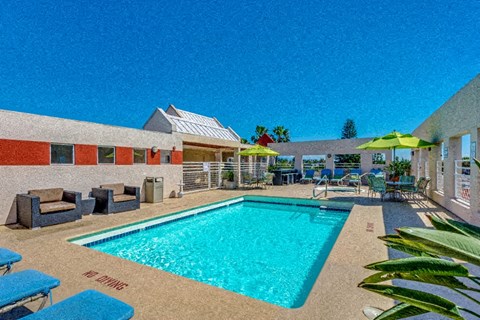 a resort style pool with chairs and umbrellas in front of a house