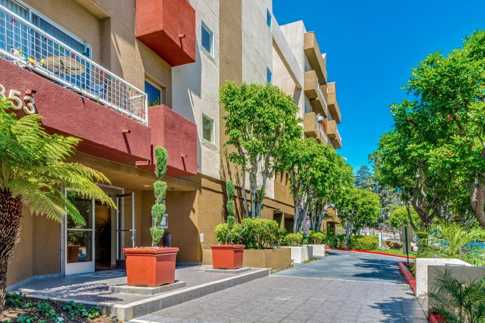 a sidewalk in front of an apartment building with potted plants