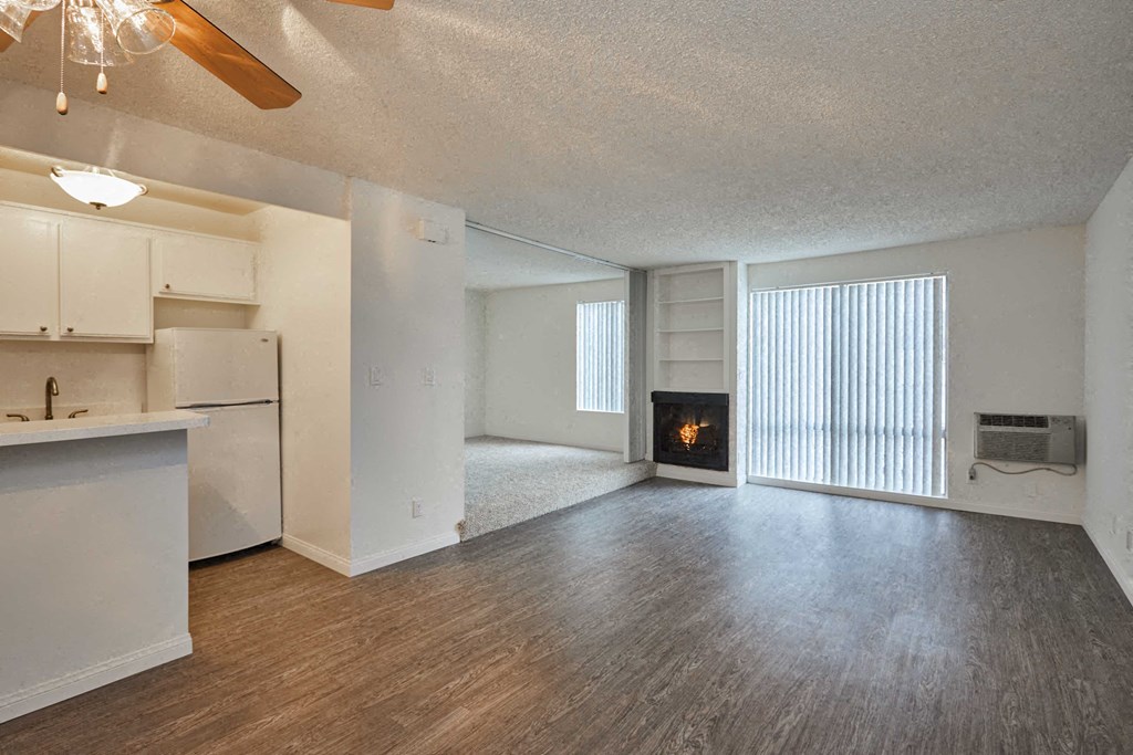an empty living room with a fireplace and a kitchen