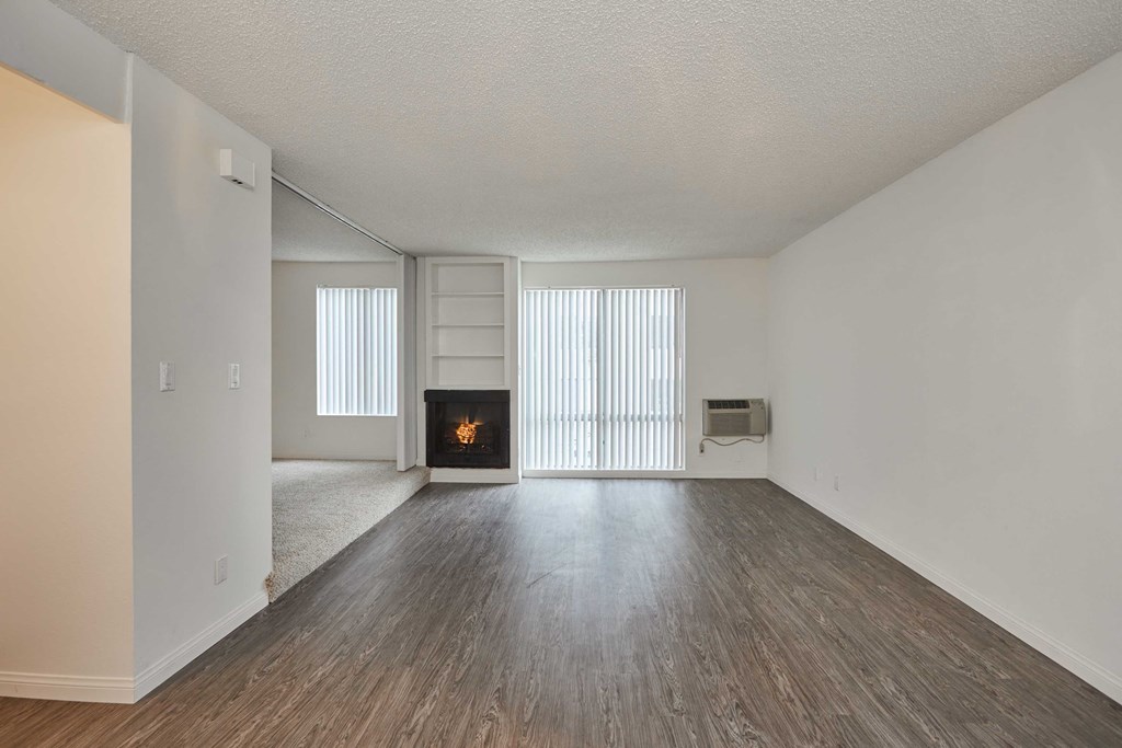 an empty living room with a fireplace and wood flooring