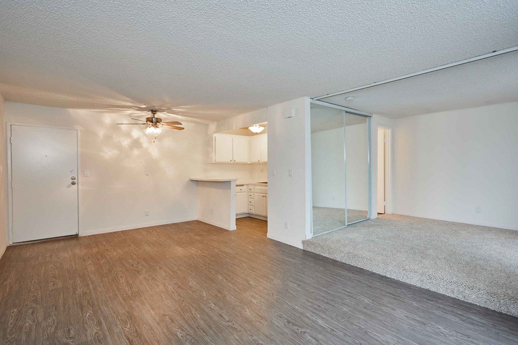 an empty living room and kitchen with a ceiling fan