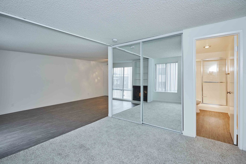 an empty living room with mirrored walls and a carpeted floor
