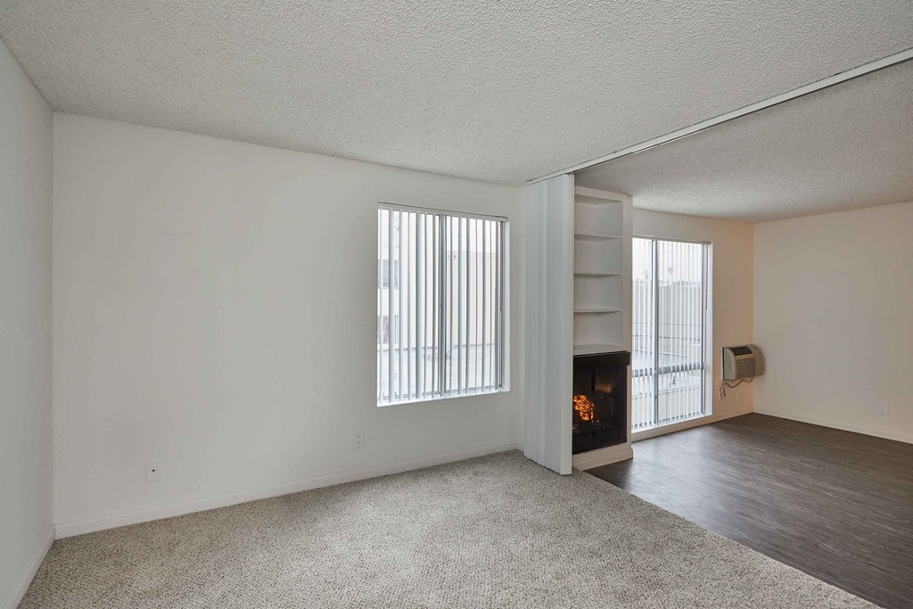 the living room and dining room of an apartment with a fireplace