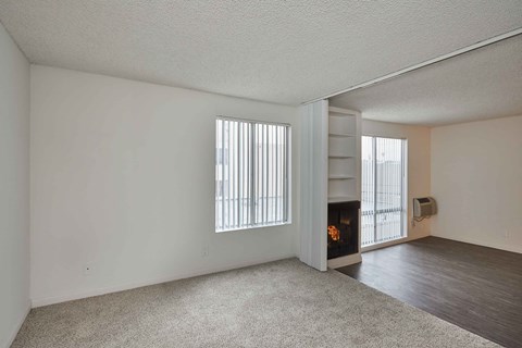 the living room and dining room of an apartment with a fireplace