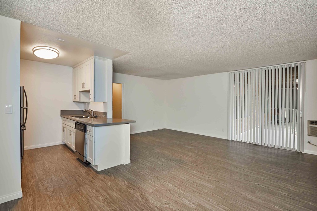 an empty living room with a kitchen with a counter top and