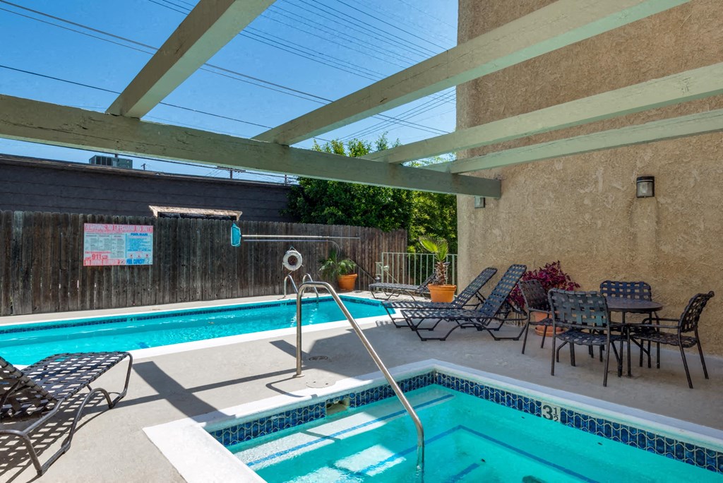 a swimming pool and patio with chairs and a poolside table