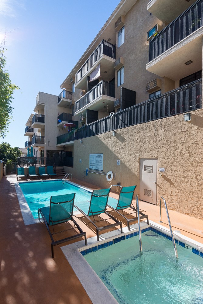 an apartment building with a swimming pool and lounge chairs