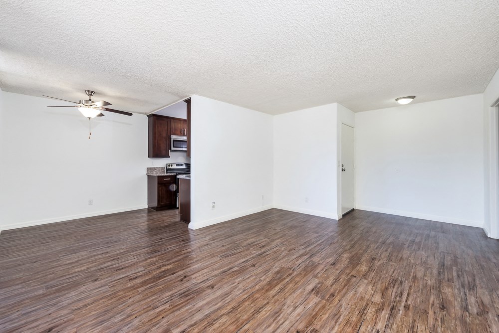 an empty living room with wood flooring and a ceiling fan