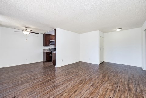 an empty living room with wood flooring and a ceiling fan